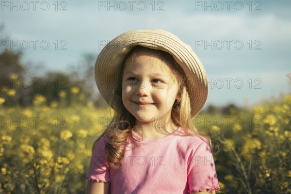 A young girl wearing a straw hat smiles warmly as she enjoys the golden sunlight in a beautiful flower field. Her happiness and innocence reflect the joy of childhood and nature