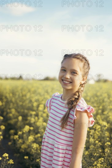 A young girl in a striped dress enjoys a moment of peace in a field of blooming yellow flowers. Embrace nature, curiosity and the beauty of childhood outdoors