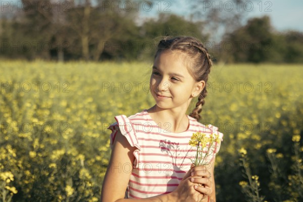 A young girl in a striped dress enjoys a moment of peace in a field of yellow flowers. Carefully pick up a bouquet of flowers, embracing nature, curiosity and the beauty of childhood outdoors