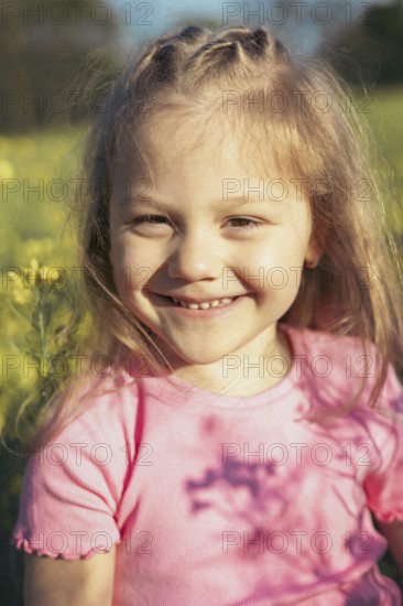 A young girl with bright eyes and a big smile enjoys a sunny day in a field of yellow flowers Her glowing face and joyful expression reflect the innocence of childhood