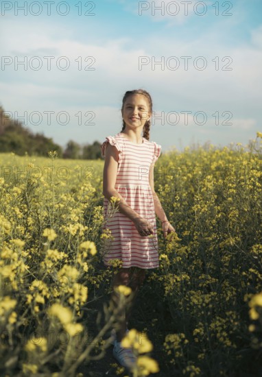 A school-age girl in a field of flowers in summer. Childhood and nature