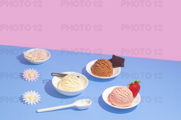 Various flavors of ice cream in white dishes, presented against a striking pink and blue background, accompanied by decorative flowers, a strawberry, and a piece of chocolate