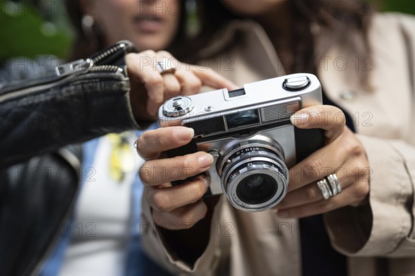 A lesbian couple shares a moment of connection through photography. Their hands hold a vintage camera, symbolizing creativity and love in an urban setting