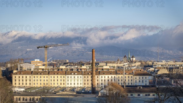 A picturesque view of Geneva, Switzerland, showcasing the city's architecture with the majestic Swiss Alps in the distance. The iconic Lake Leman adds to the serene landscape