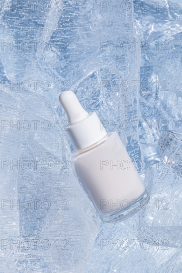 A frosted glass serum bottle with a dropper, cradled by sparkling chunks of ice, emphasizing cooling skin-care treatments