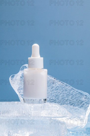 A single serum bottle with a dropper rests on clear ice chunks against a vibrant blue background, illustrating a theme of freshness and purity in skincare
