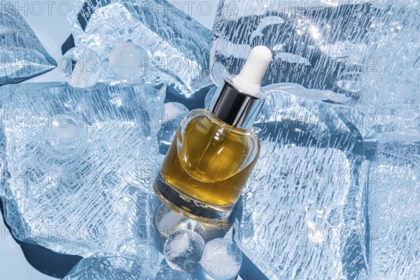 A serum bottle with a dropper is elegantly placed amidst scattered ice cubes, showcasing a luxurious skincare essential in a chilled setting