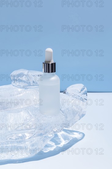 A frosted glass serum bottle with a dropper, resting in a carved ice block on a vibrant blue background, emphasizing cool freshness