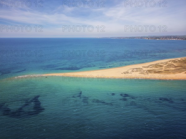 Aerial view of Epanomi Sandbar Beach on the coast of Greece. The golden sand stretches into the turquoise waters, creating a stunning contrast with the deep blue sea under a clear sky