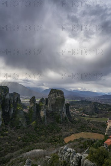 Panoramic view of Meteora's towering rock formations and ancient monasteries in Kalabaka, Greece, under a moody sky. A UNESCO World Heritage Site of spiritual and natural beauty