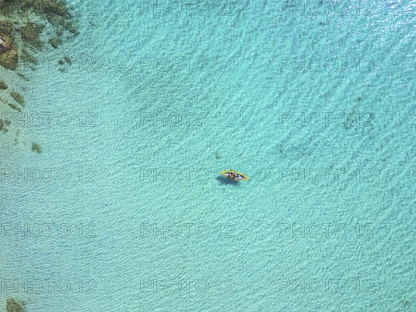 A stunning aerial view of Diaporos Island in Greece, showcasing crystal-clear turquoise waters with a lone kayak drifting peacefully. A paradise of wild beaches and untouched nature