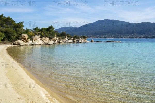 A pristine beach on Diaporos Island in Greece with turquoise waters and golden sand. Surrounded by rocky formations and lush greenery, it offers a peaceful and unspoiled natural escape