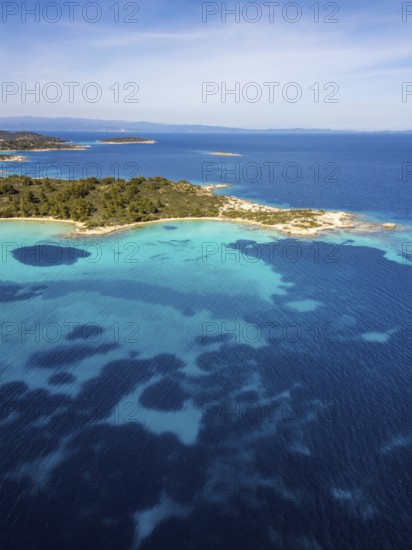 Aerial view of Diaporos Island and Karydi Beach, Greece, with bright turquoise waters, green forests, and rocky shores. A breathtaking Mediterranean coastal scene under clear skies
