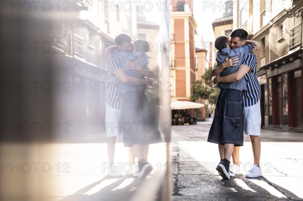 A loving embrace between a gay couple on the charming streets of Madrid. The scene captures a tender moment filled with joy and pride, set against a sunny urban backdrop