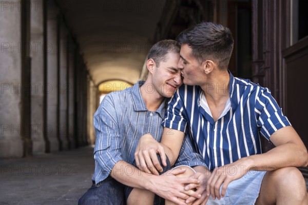 A loving gay couple shares an affectionate moment on the picturesque streets of Madrid. Their embrace reflects pride and a celebration of their relationship