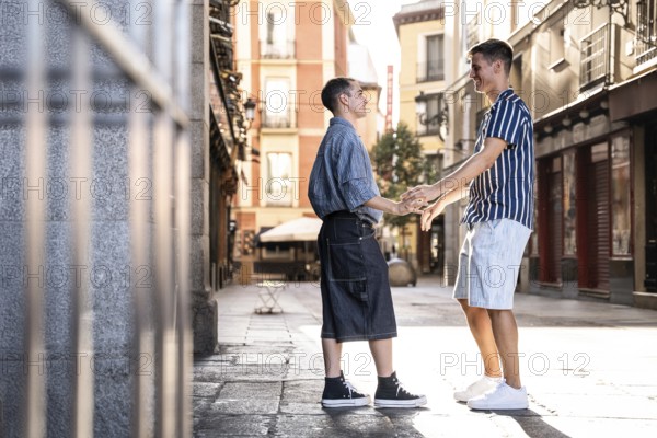 A romantic and joyful moment shared by a gay couple holding hands on a sunny street in Madrid, showcasing love and happiness in an urban setting