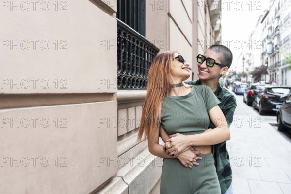 Colombian lesbian couple sharing a joyful embrace in a vibrant city street, showcasing love, happiness, and diversity. Expressing freedom and equality in LGBTQIA+ community