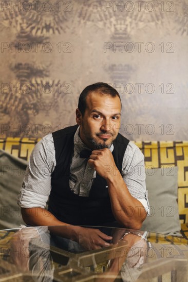 A professional bartender poses confidently in an upscale cocktail bar. Wearing a smart vest and shirt, he embodies elegance and expertise in mixology and hospitality