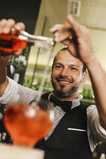 A professional bartender skillfully pours a vibrant cocktail in a busy bar. The image captures the essence of mixology, highlighting expertise and atmosphere