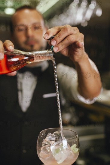 A professional bartender skillfully mixing cocktails in an elegant club with a bar spoon. The vibrant scene captures the art of cocktail-making with precise ingredients and techniques
