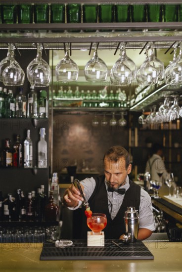 A professional bartender skillfully prepares a vibrant cocktail at an elegant urban bar, surrounded by an array of liquor bottles and glassware, showcasing mixology art