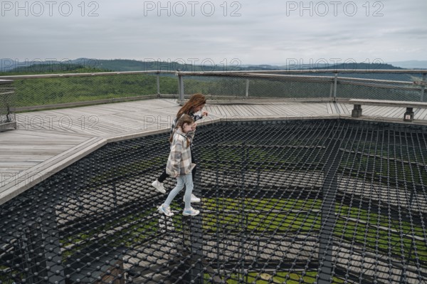 Cheerful woman and her child traversing the treetop walk at Bachledka in Slovakia