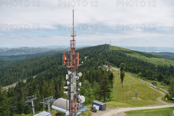 Aerial view showcasing the expansive Bachledka Ski and Sun in Zdiar, Slovakia, featuring lush green landscapes, a prominent communication tower, and the picturesque Belianske Tatras in the background