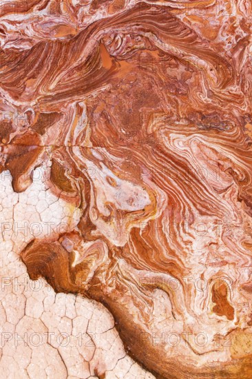 Close-up view of intricately patterned red and white rock surfaces, showcasing swirling colors, natural textures, and cracked patterns