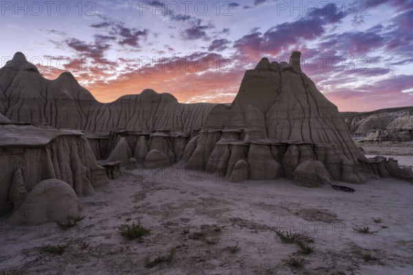 Stunning sunset illuminating the unique rock formations in the Bisti/De-Na-Zin Wilderness in New Mexico, showcasing nature's artistry in geology