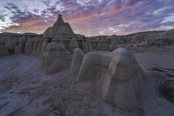Dramatic sunset illuminating the unique rock formations of Bisti/De-Na-Zin Wilderness in New Mexico, USA, showcasing nature's artistry in the desert landscape