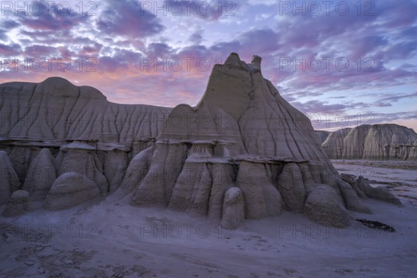Sunset casts a soft glow over the dramatic and weathered sandstone formations of the Bisti/De-Na-Zin Wilderness in New Mexico, highlighting its unique geological features