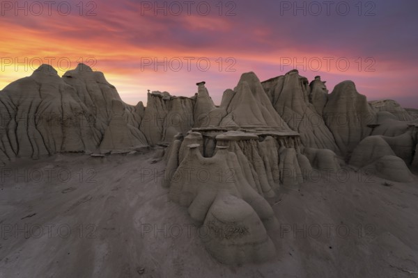 Stunning sunset over the unique rock formations in Bisti/De-Na-Zin Wilderness, New Mexico, USA, highlighting the area's ethereal desert beauty