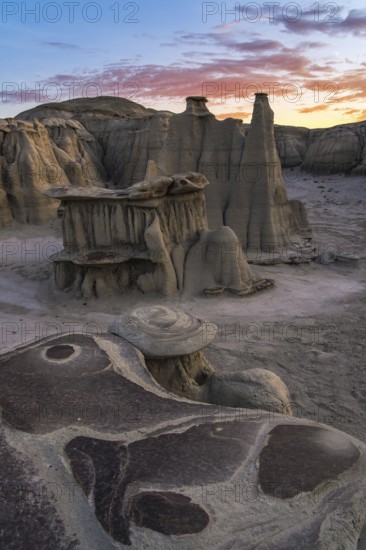 Majestic hoodoos and textured rock formations glow under a sunset sky in Bisti/De-Na-Zin Wilderness, New Mexico, USA, showcasing nature's artistry