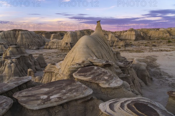 Spectacular sunrise highlighting the unique hoodoo formations in the Bisti/De-Na-Zin Wilderness of New Mexico, USA, showcasing the area's dramatic and alien landscape