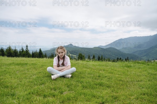 Young girl resting on a grassy hill with a stunning view of the Belianske Tatras, seen from Bachledka in Slovakia