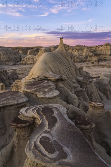 A stunning sunset illuminates the unique rock formations and hoodoos in the Bisti/De-Na-Zin Wilderness of New Mexico, highlighting incredible natural patterns and colors