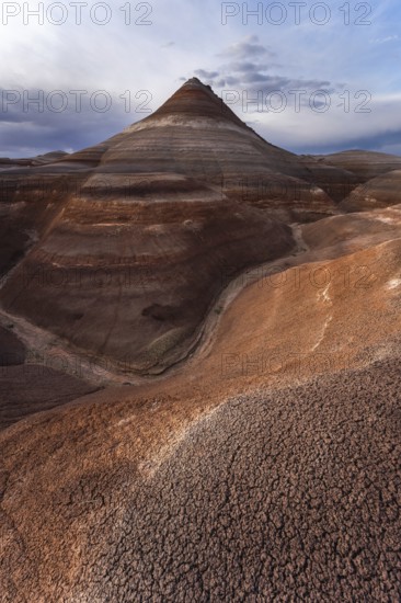 Striking view of layered bentonite hills in Hanksville, Utah, showcasing unique geological formations under a vast, cloudy sky, capturing nature's raw beauty and texture