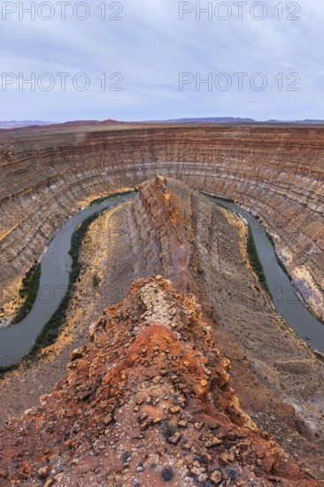 Stunning aerial view of a San Juan canyon featuring a winding river carving through layered rock formations. The rich earthy tones highlight the geological wonders of the landscape in Utah, USA