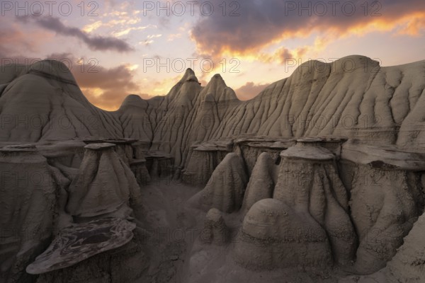 Captivating sunset illuminates the unique sandstone hoodoos in the Bisti/De-Na-Zin Wilderness in New Mexico, showcasing nature's artistry under a vibrant sky