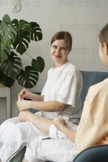 A mother and daughter share a bonding moment as they pamper each other with foot care in a cozy home setting. The scene illustrates relaxation and familial connection