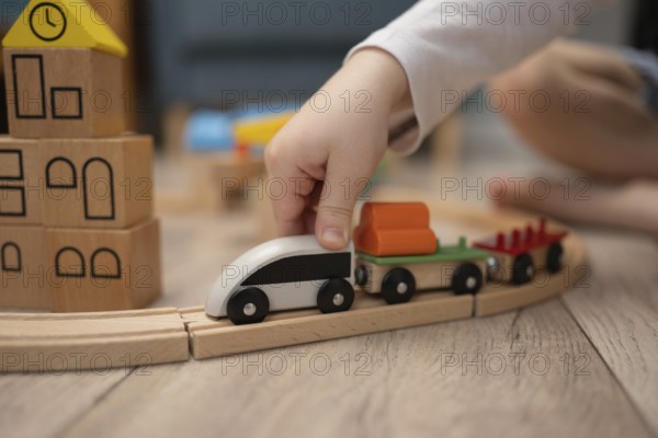 A child hand guides a wooden toy train along a curved track, surrounded by colorful building blocks in the background. Perfect image for playtime and imagination