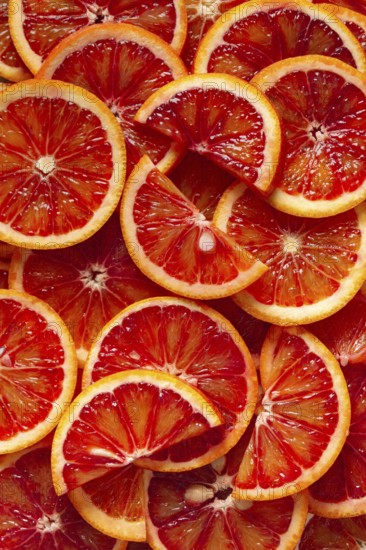 A close-up view of freshly sliced blood oranges revealing vibrant red and orange hues. The juicy segments create a pattern, highlighting natural beauty and texture