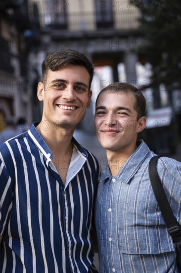 A joyful gay couple enjoying a sunny day on the bustling streets of Madrid, showcasing pride and happiness. Vibrant city life and diverse culture surround them