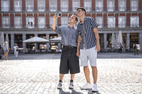 A gay couple enjoys a sunny day in Madrid, capturing memories on the bustling streets while holding hands. The scene reflects love, pride, and togetherness