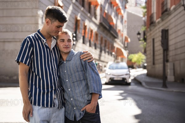 A joyful gay couple embraces in the sunny streets of Madrid, celebrating love and togetherness. The vibrant urban backdrop adds a charming touch to their intimate moment