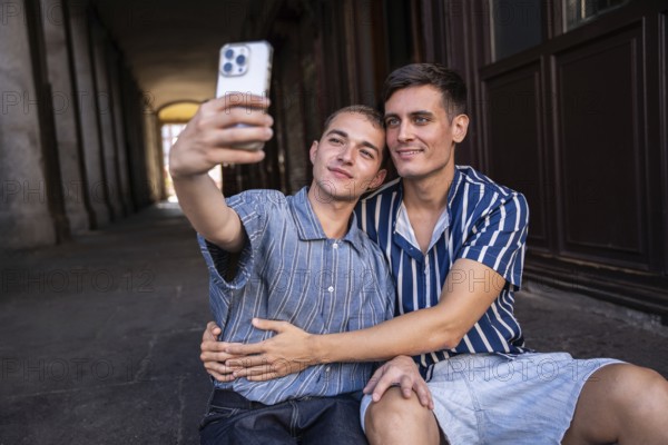 A joyful gay couple captures a selfie moment on the lively streets of Madrid. Embracing love and pride in their vibrant surroundings