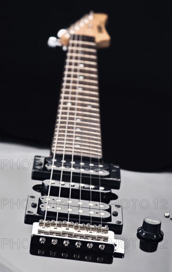 Close up of an electric guitar showcases sleek design and detailed focus on strings. Emphasizes craftsmanship and artistry, ideal for music enthusiasts and creative projects