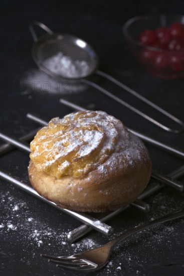 A delectable freshly baked cream bun, generously filled with smooth cream and dusted with fine icing sugar, presented on a dark cooling rack