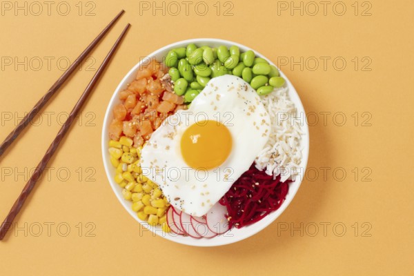 A colorful poke bowl featuring fresh ingredients like edamame, corn, salmon, beets, and a sunny side up egg, elegantly presented with chopsticks on a warm background