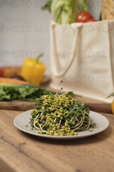 A fresh topped with green sprouts on a white plate sits on a wooden table. In the background, assorted vegetables and a reusable bag add a vibrant touch